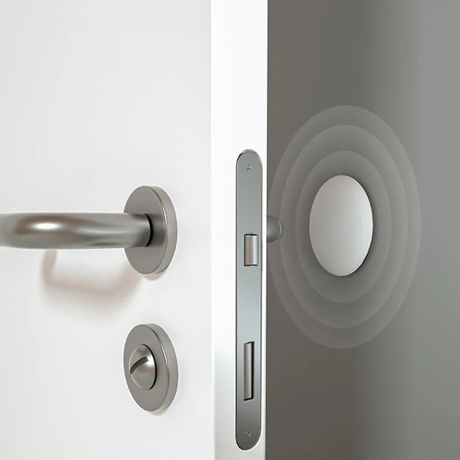 Butée de porte carrée adhésive installée près d’une poignée métallique sur une porte blanche — protège le cadre contre les chocs du mécanisme de fermeture.