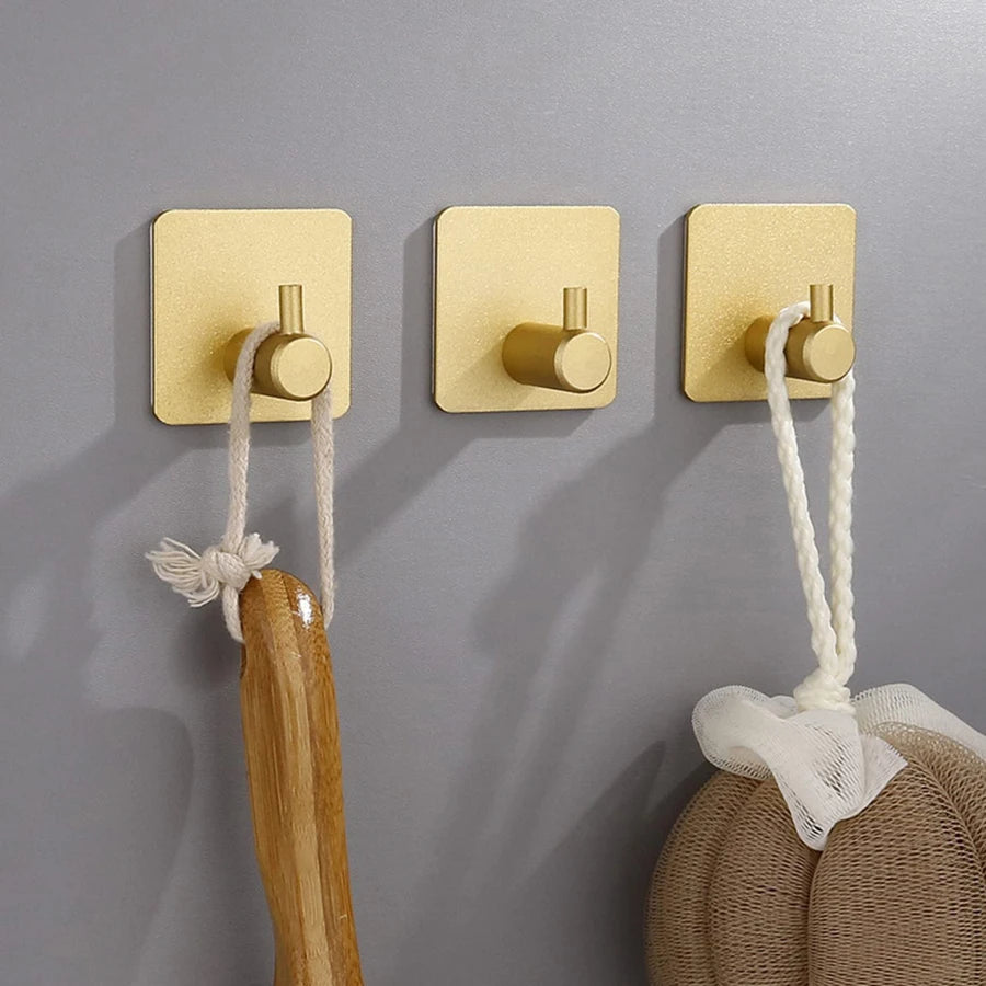 Crochets muraux adhésifs en acier inoxydable, fixés sur une paroi grise. Design moderne et épuré, utilisés pour suspendre une corde et une serviette , une brosse. Conviennent à la salle de bain, cuisine ou espace de rangement.