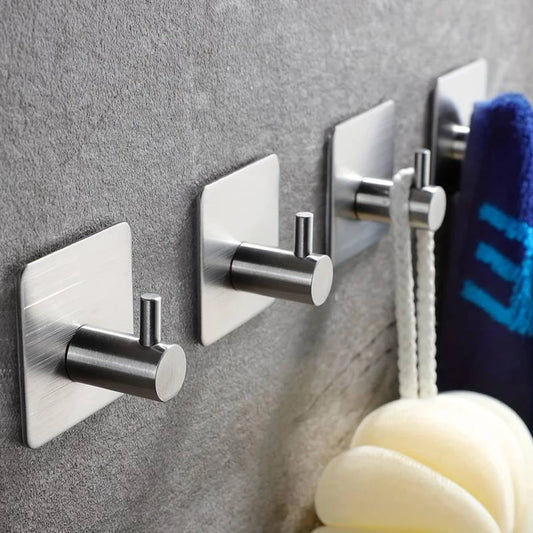 Crochets muraux adhésifs en acier inoxydable, fixés sur une paroi grise. Design moderne et épuré, utilisés pour suspendre une corde et une serviette. Conviennent à la salle de bain, cuisine ou espace de rangement.