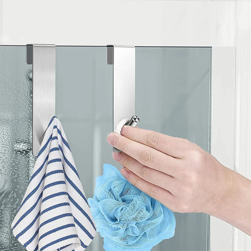 Crochet en acier inoxydable suspendu sur une porte de douche en verre trempé — utilisé pour accrocher une serviette et une éponge de bain, fixation sans perçage, pratique et amovible.
